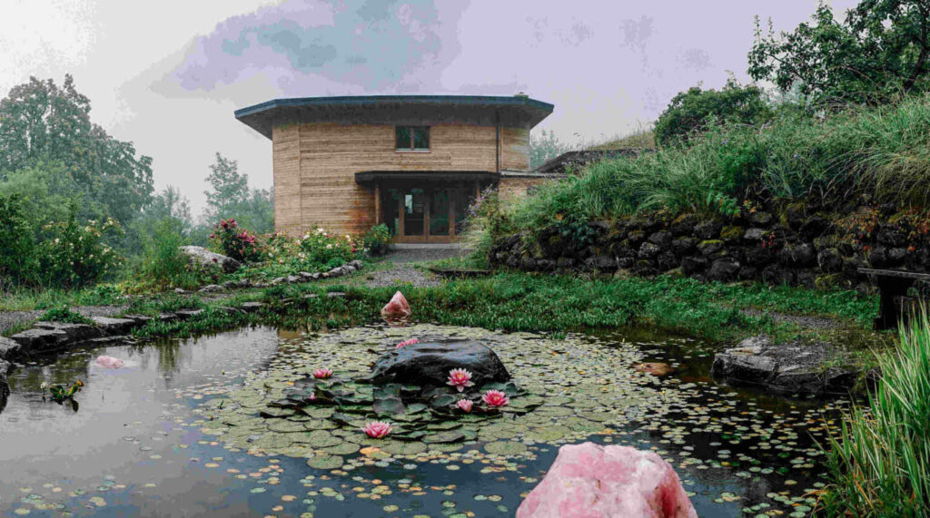 Seerosenteich in saftig grüner Schweibenalp. Dahinter der Eingangsbereich des Seminarhauses