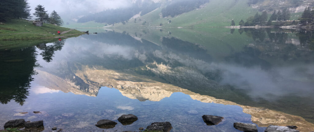 Spiegelglatte Seeoberfläche mit Abbild der Berge.